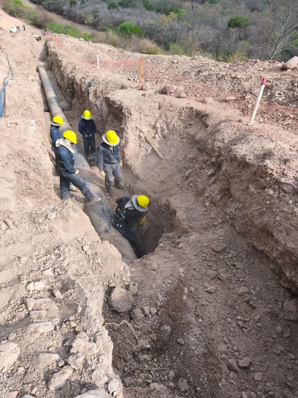 Cuadrilla instalando cañería en zanja de obra